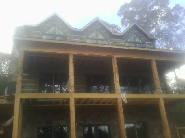 Dormers and porch framing on a large log home under construction — Roof Coating work by our crew in Baxter
